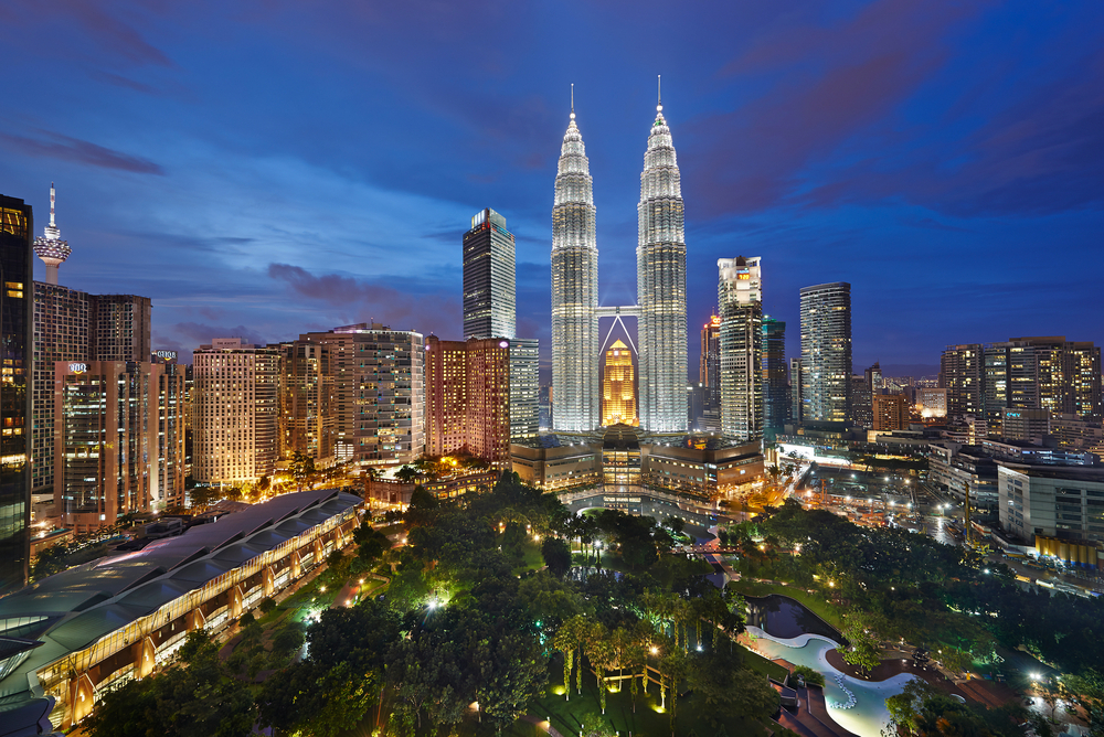Photograph of Kuala Lumpur, lit up against a blue and purple night sky