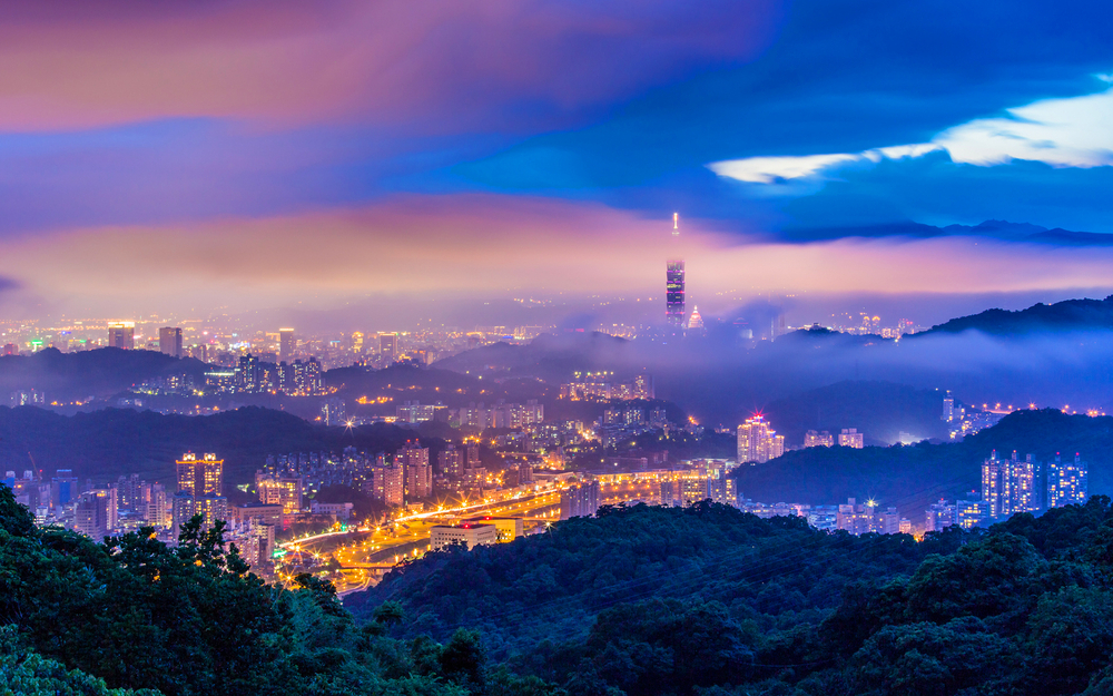 Mystifying photograph of Taipei, city lights reflect off heavy mists against a purple sunset