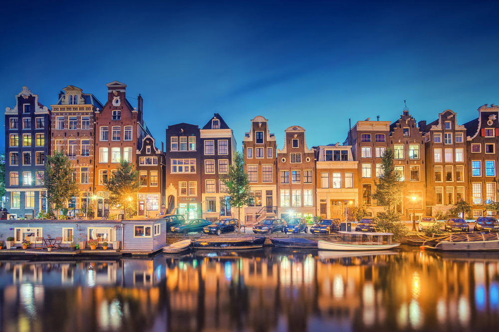 Photograph of Amsterdam lit up at night, as seen from the canals