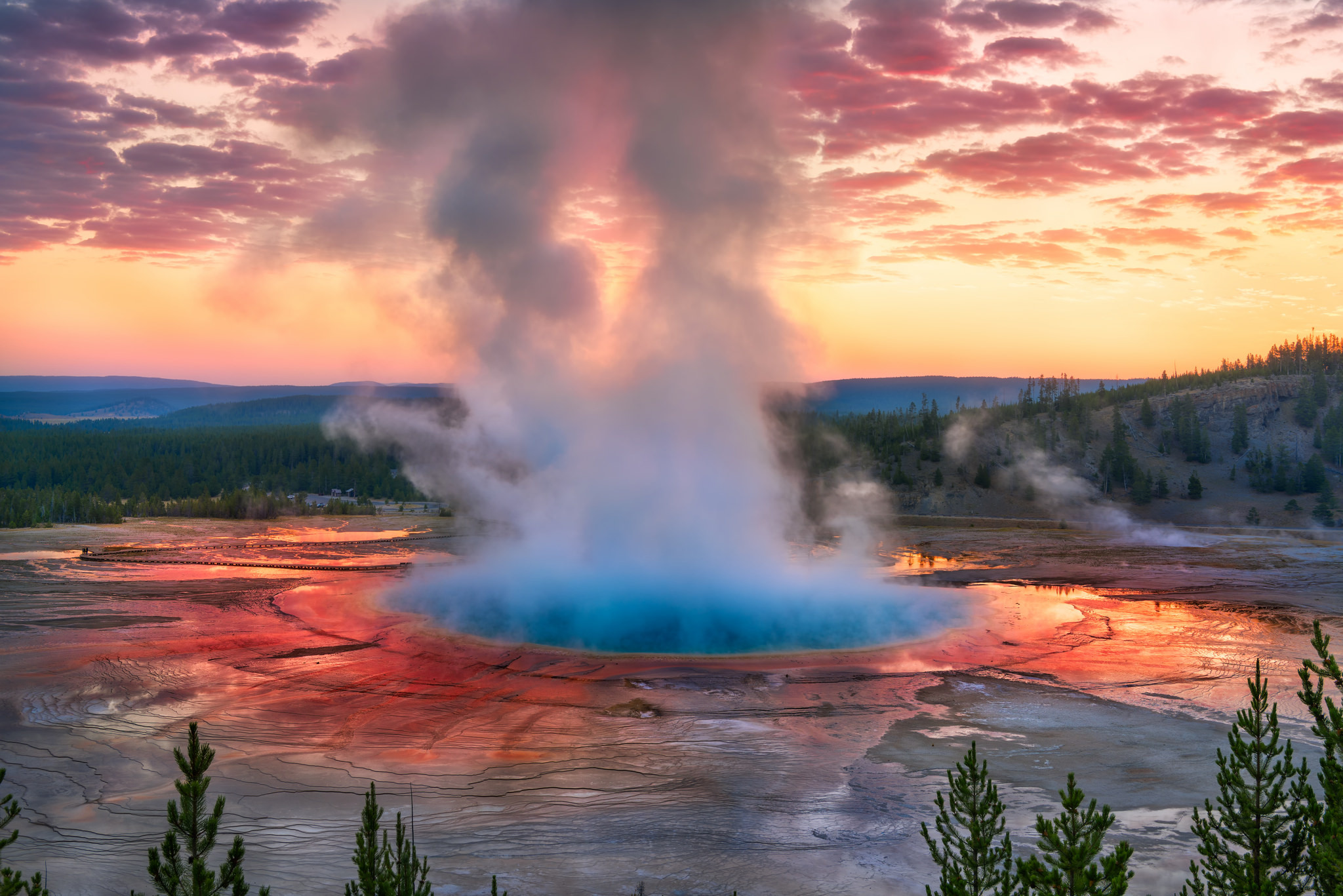A geyser sprays water and vapour at sunset