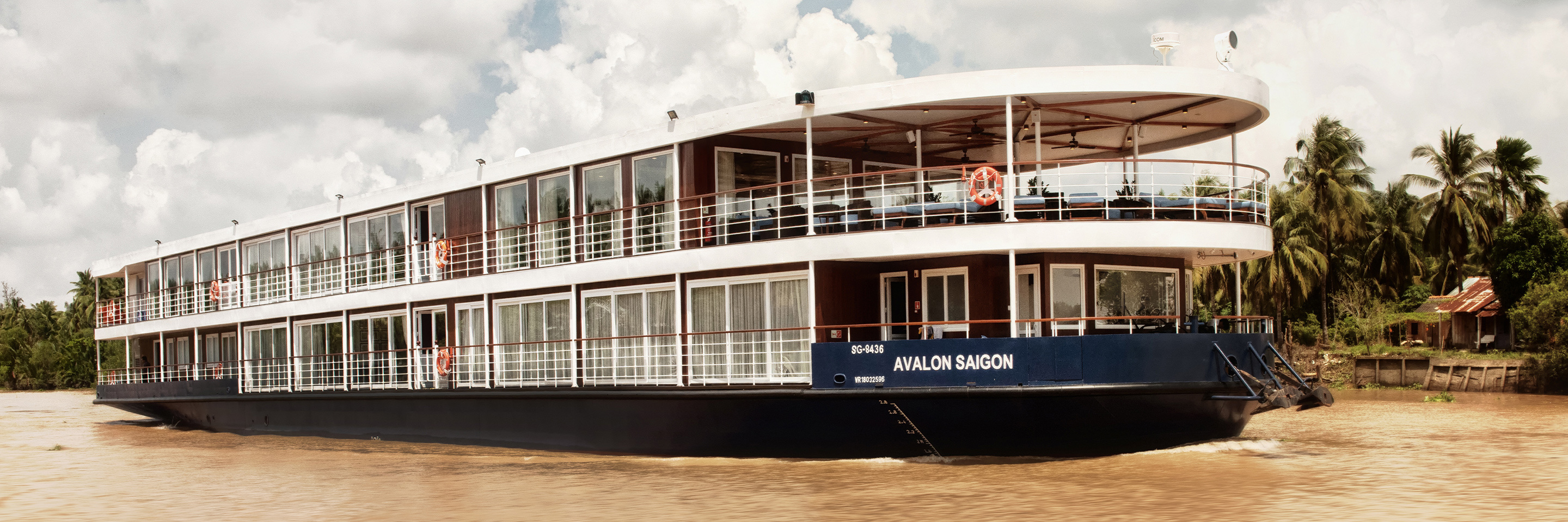Photograph of the Avalon Saigon river cruiser, as it travels through jungle waters