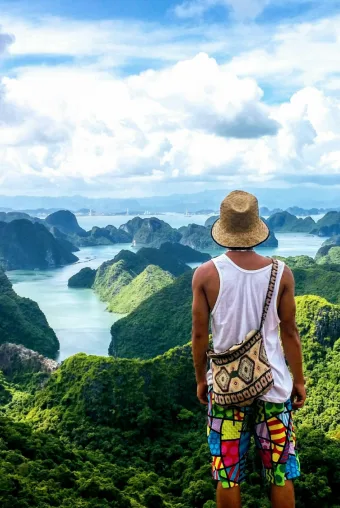 Photograph of a tan skinned traveler looking out from an Asian overlook at lush green landscapes, taken by photographer Ngoc Vuong