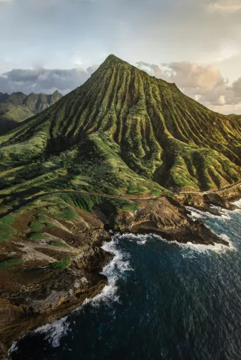 Photo of Hawaiian Island, lush green forests cover a mountain surrounded by turquoise waters